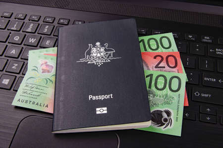 australian passport and bank notes on a black computer keyboard