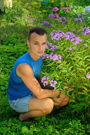 A young man about Bush Phlox on the plot in the summer on a Sunny day close upの写真素材