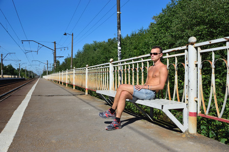 A young man waiting for the train on an empty commuter train platform in Virica