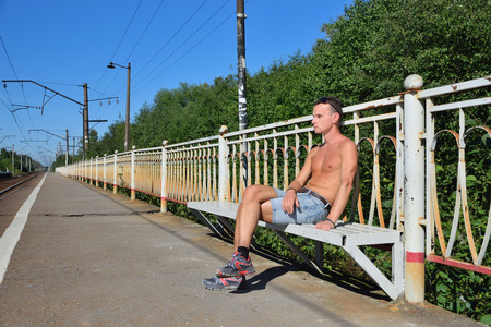 A young man waiting for the train on an empty commuter train platform in Viricaの写真素材