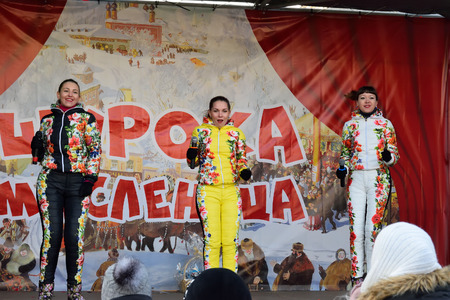 ST.PETERSBURG, RUSSIA - MARCH 13, 2016: The spectators in the performance of vocal female trio in multi-colored jumpsuits on the street on the holiday of Maslenitsa at Moscow squareのeditorial素材