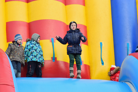 ST.PETERSBURG, RUSSIA - MARCH 13, 2016: Joyful children ride on inflatable colorful slide in the shape of a dragon on the holiday of Maslenitsa at Moscow squareのeditorial素材