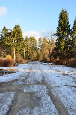 View suburban street with melting snow in spring on a Sunny day in the village of Vyritsa of the Leningrad regionの写真素材