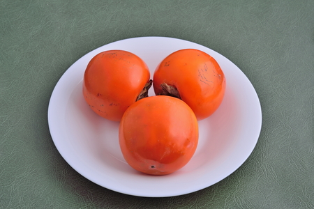 Persimmon fruit on a white plate on the table.の写真素材