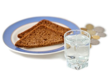 A shot of vodka in the background of a piece of bread and metal coins.の写真素材