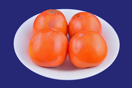 Persimmon fruit on white plate on blue background.の写真素材