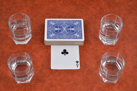 A deck of playing cards and stacks of vodka on the table.
