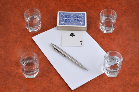 A deck of playing cards, pen, paper and stacks of vodka on the table.の写真素材