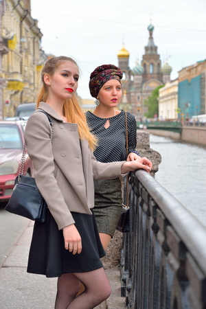 Attractive girl standing on the Griboyedov Canal embankment in front of the Cathedral of the Savior on Blood in Saint-Petersburgの写真素材