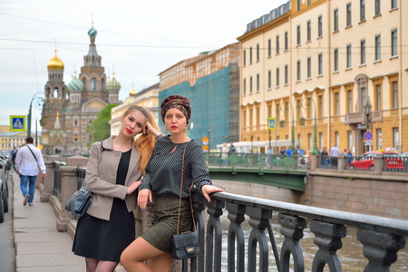 Beautiful tourists rest at the gate of the Griboyedov Canal embankment in front of the Cathedral of the Savior on Blood in Saint-Petersburgの写真素材