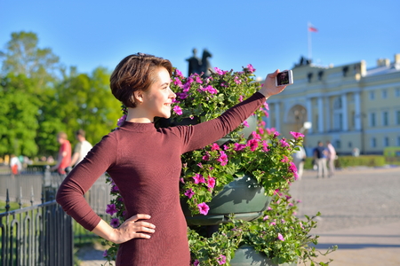 A young girl makes a selfie from the flower beds on the background of the monument bronze Horseman in Saint-Petersburg.の写真素材