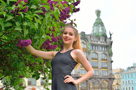 Beautiful girl smiling Bush of purple lilacs in the background of the book - singer in Saint-Petersburgの写真素材