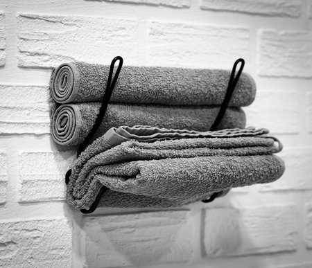 Gray Towels on a White Wall in a Metal Holder. Personal Care Items in the Bathroom.の写真素材