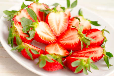 Ripe Strawberries in a White Plate. Fresh Juicy Strawberries with Leaves. Summer Berries Background.の写真素材