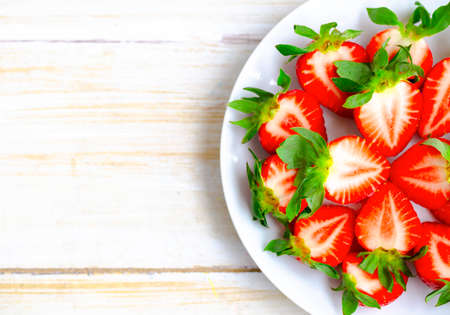 Ripe Strawberries in a White Plate. Fresh Juicy Strawberries with Leaves. Summer Berries Background.の写真素材