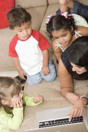 Portrait of family, mom and children enjoying indoor with a laptop