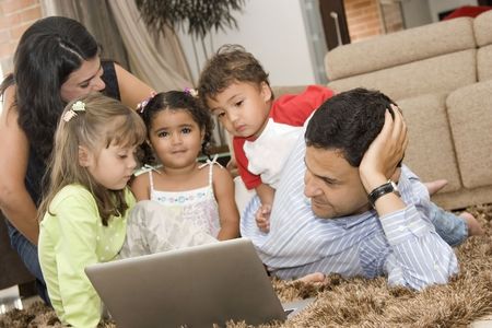 Portrait of family, mom, dad and their children enjoying indoor with a laptopの写真素材