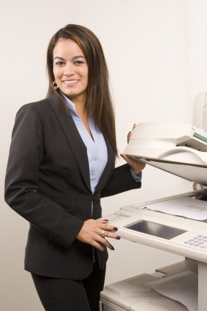 Young young businesswoman making copies on the photocopy machine at the officeの写真素材