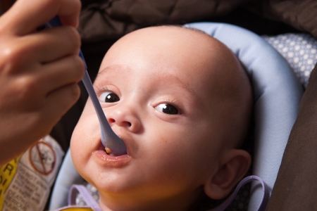 Portrait of a Mother Feeding Her Sweet Baby Boy, With Spoonの写真素材