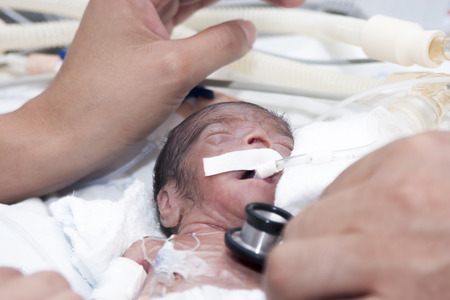 Portrait of newborn baby and hand inside incubator