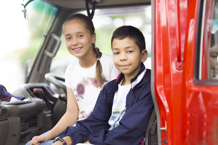 Happy Girl and Boy in Firefighter Car Enjoying Outdoors
