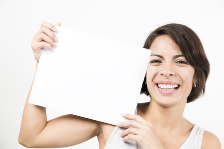 Beautiful young woman holding a blank sheet of paper. Space for your text. Isolated on white.の写真素材