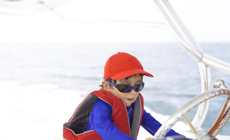 Happy boy driving a boat, enjoying summerの写真素材
