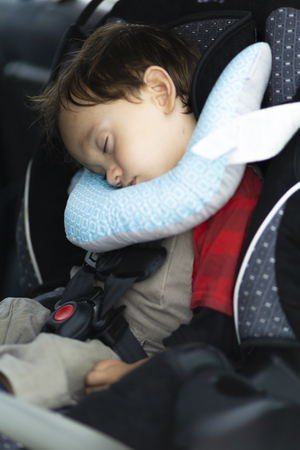 Happy Mother helping her son to fasten, seatbelts in the carの写真素材