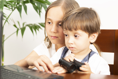Happy Girl and  Boy Sitting at his Desk With Laptop Computerの写真素材