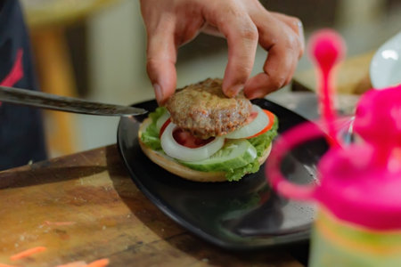 Chef ready to serve burger, on kitchen utensils background. Delicious food, fast food, homemade recipes, restaurant, catering, cookbooksの写真素材