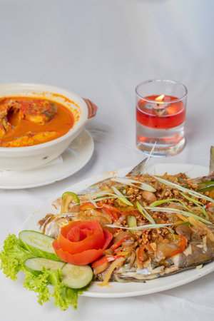 steamed pompano or kuwe fish with sweet and spicy sauce and beautiful garnishesの写真素材