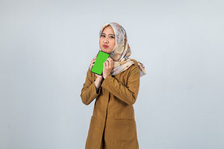 Cute Young Indonesian Woman government employee wearing a brown uniform while showing a mobile phoneの写真素材