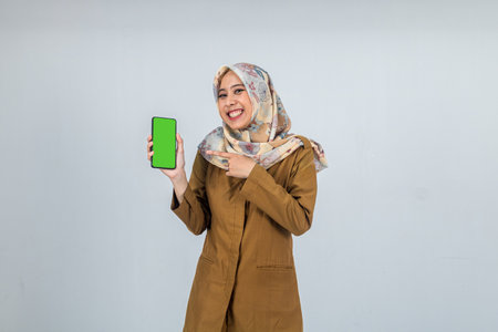 Young Indonesian Woman government employee wearing a brown uniform while showing and pointing to mobile phoneの写真素材
