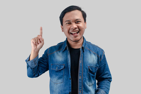 Young asian man pointing hand up to empty space on isolated background