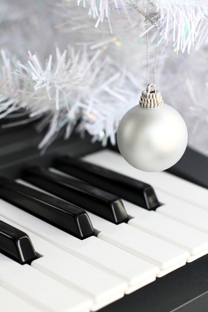 Image of a piano with shiny Christmas decoration ball hanging from a stringの写真素材
