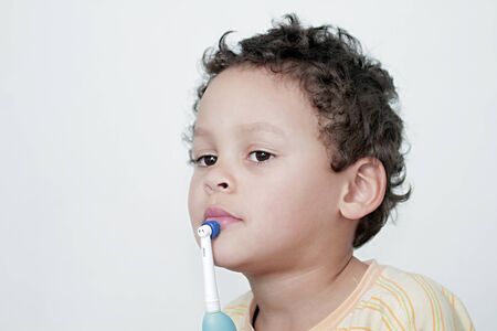 little boy brushing his teeth with an electric tooth brush stock image with white background stock photoの写真素材