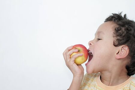 little boy eating apple with white background stock photoの写真素材
