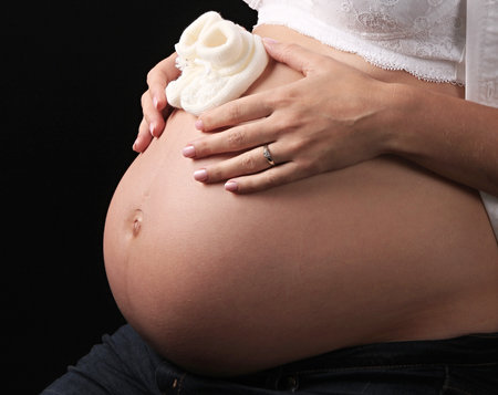 pregnant woman with hands on her belly stroking her baby with love and care stock photoの写真素材