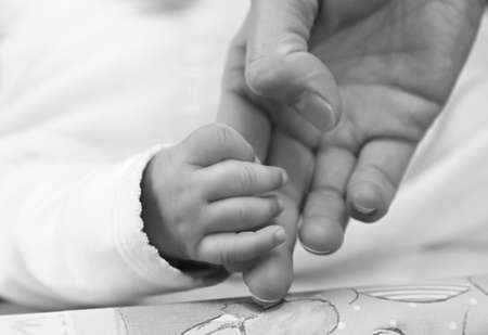 mother holding baby hand in bed stock photography stock photo