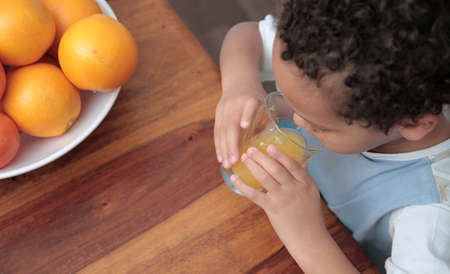 child drinking a glass of orange fruit juice promoting healthy eating stock photoの写真素材