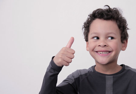 boy showing the thumbs up gesture on white grey background stock photoの写真素材