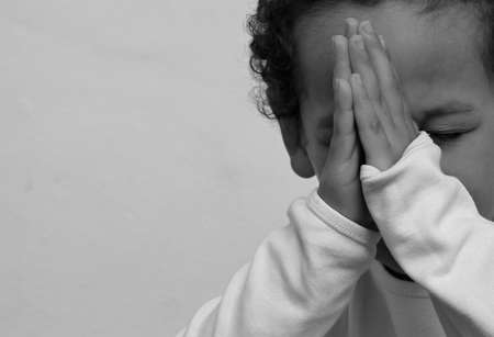 boy praying to God with hands together on white background stock photoの写真素材