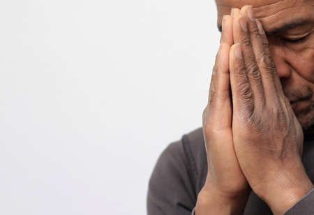 man praying to god with hands together Caribbean man praying with white background stock photo