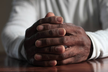 man praying to god with hands together Caribbean man praying with black background stock photos...