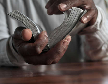 man praying with hand on bible black background stock photoの写真素材