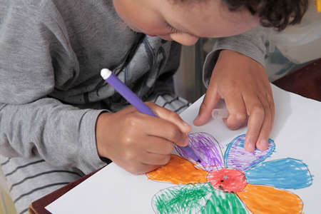 Child drawing with colored pencils on white paper, close-upの写真素材