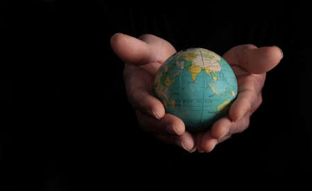Human hand holding a globe on black background. Save the planet conceptの写真素材