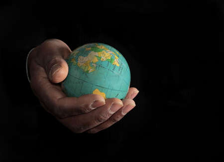 Human hand holding a globe on a black background with copy space.の写真素材