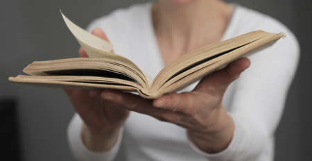 Close-up of an open book in the hands of a womanの写真素材