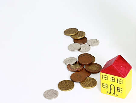 House and coins on a white background. The concept of saving money for the future.